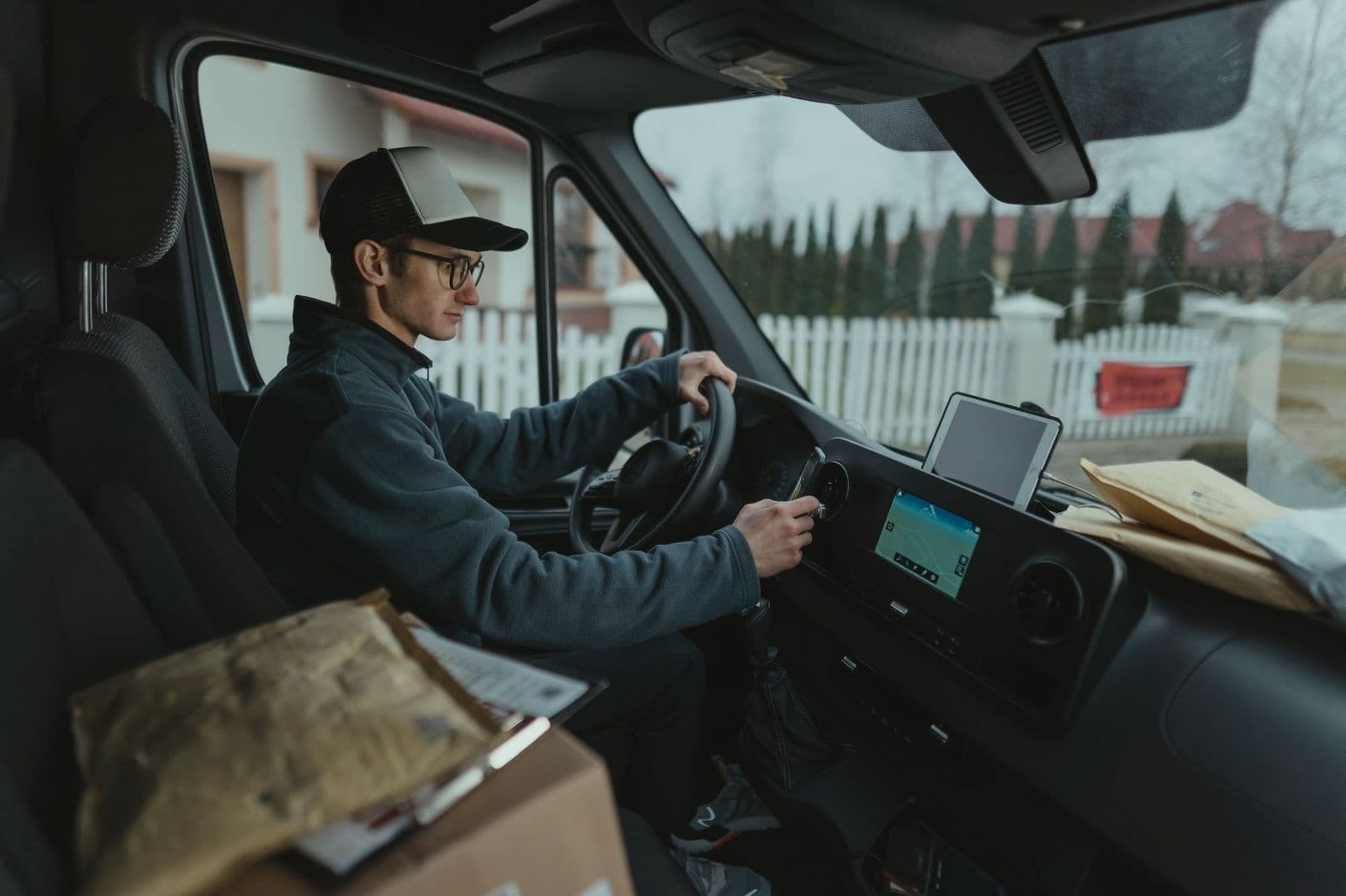 A driver seated in a vehicle cab checking a mounted device before setting off