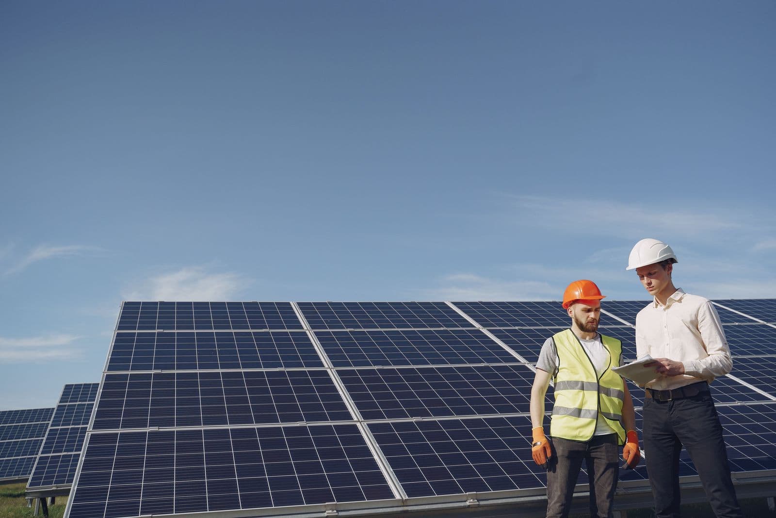 Two technicians in hard hats reviewing work at an outdoor installation site