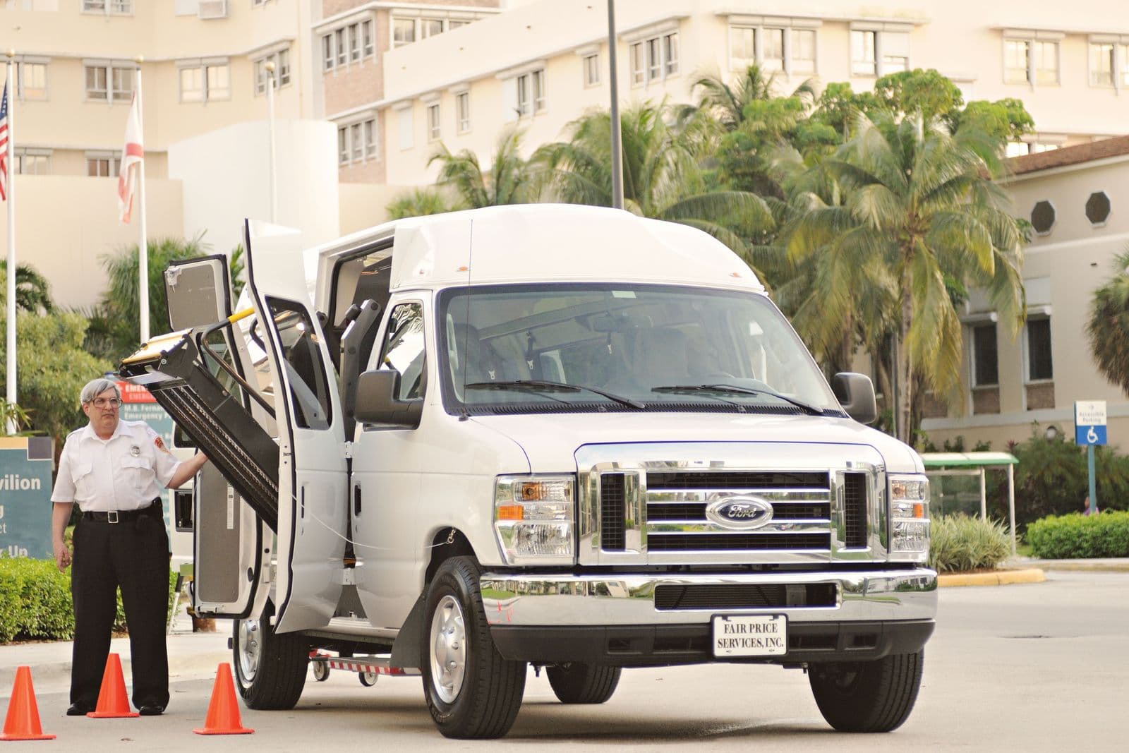 A white accessible transport van parked with its powered lift platform deployed